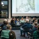 Publikum in einem Raum vor einer Bildschirmpräsentation