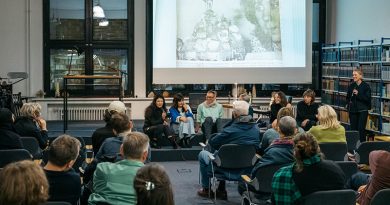 Publikum in einem Raum vor einer Bildschirmpräsentation