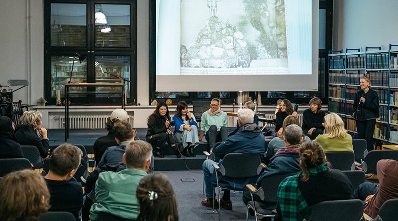 Publikum in einem Raum vor einer Bildschirmpräsentation