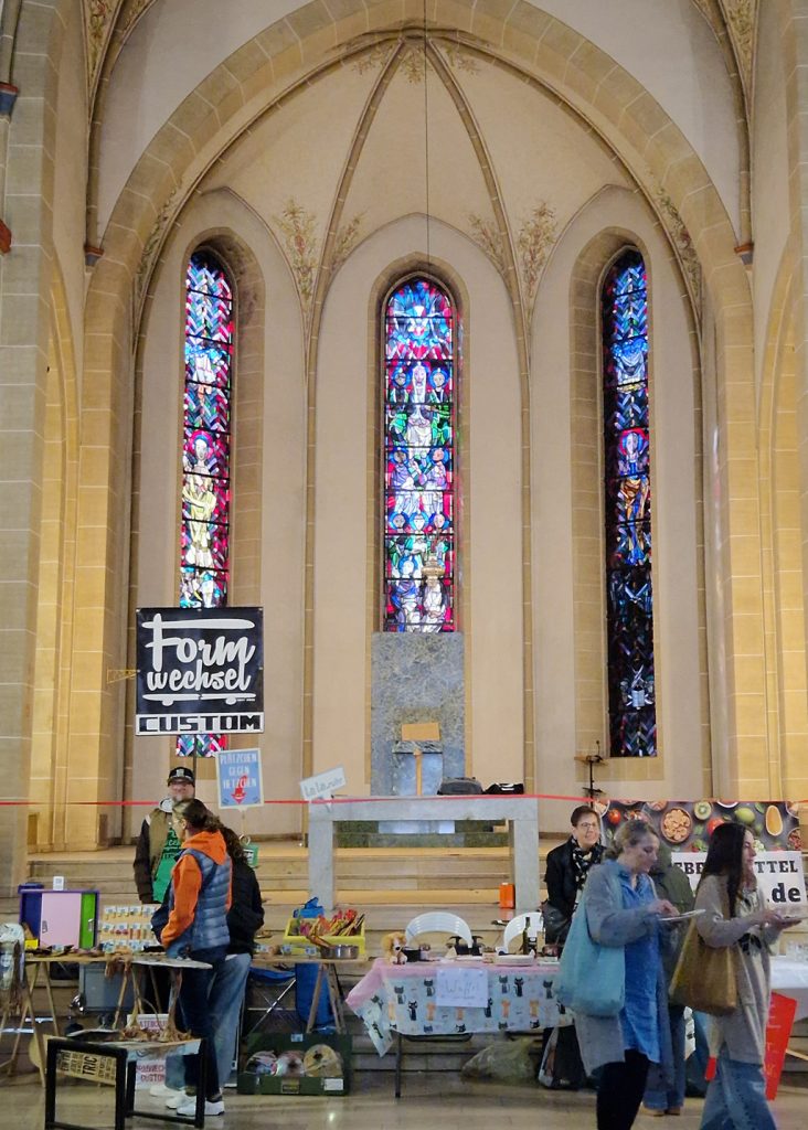 Kreativmarkt mit drei Kirchenfenstern im Hintergrund