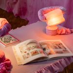 Kunstinstallation mit Tisch, Lampen und Literatur